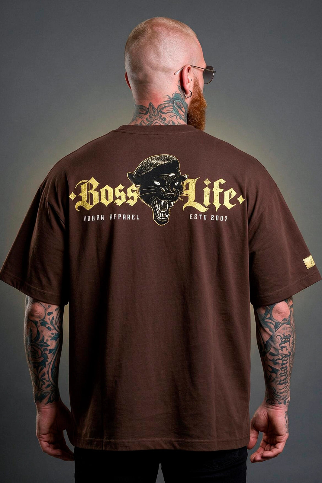 Modelo vestindo a Camiseta Oversized Panther Urban Boss Life café - costas com pantera e lettering dourado